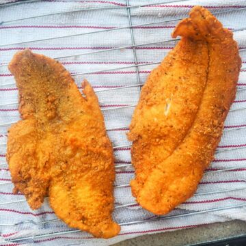 two fried catfish filets on a red and white towel