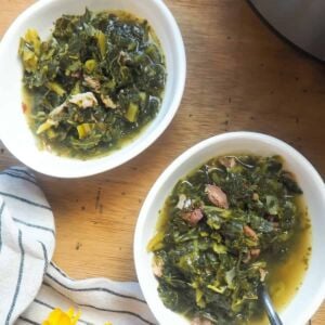two bowls of collard greens with bits of ham and bacon.