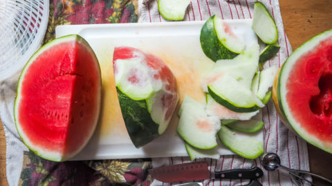 A quarter of a watermelon with the skin being cut off.