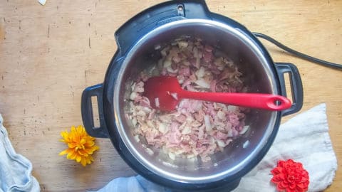 bacon, ham, and onions cooking in an instant pot.