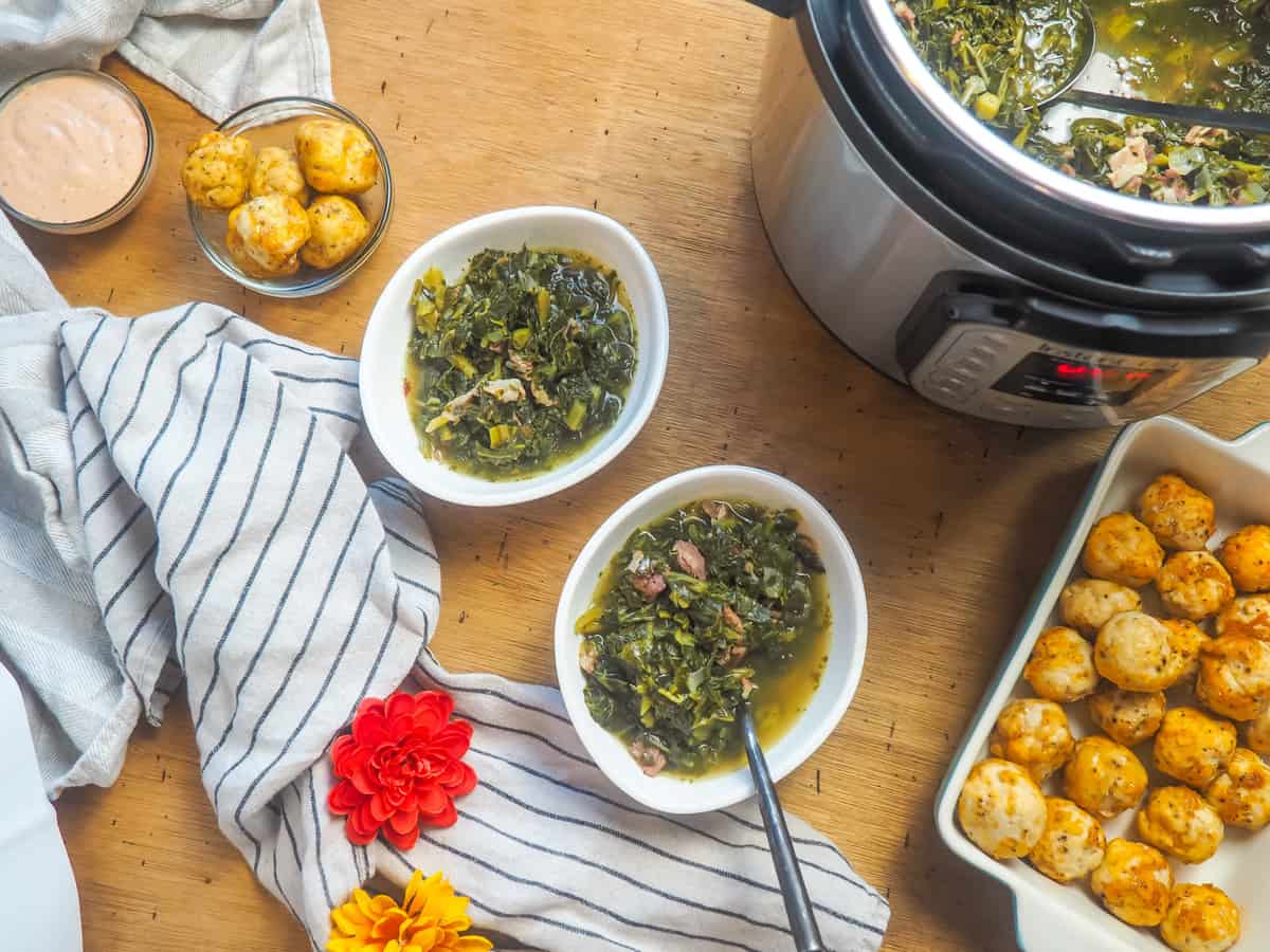 two bowls of collard greens next to an instant pot of collard greens and a pan of fried chicken balls.