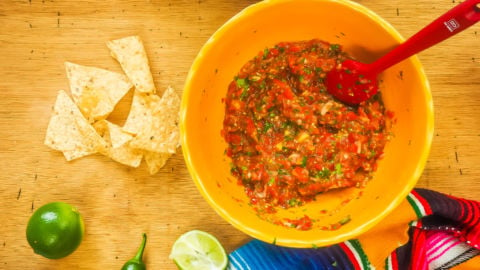 A yellow bowl of cherry tomato salsa and tortilla chips.