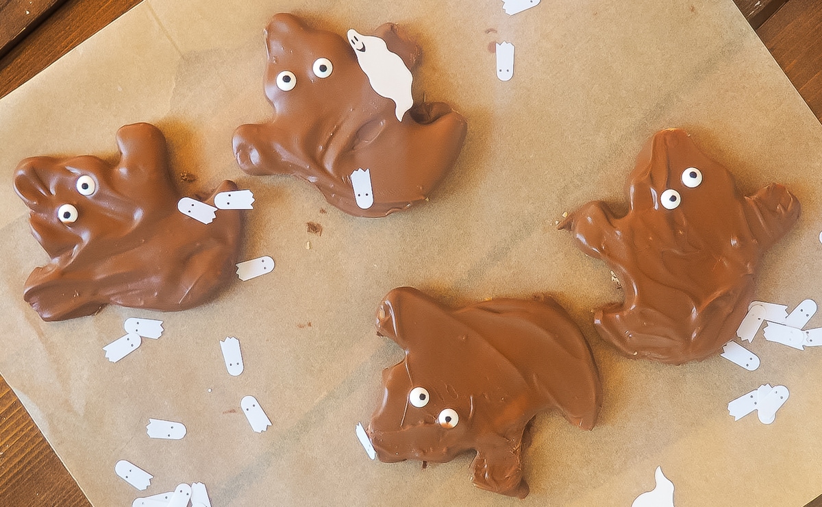 Four homemade Reese's peanut butter cup ghosts on brown parchment paper.