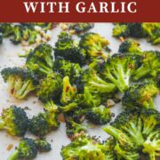 A pin image of a cookie sheet with roasted broccoli and garlic on it.