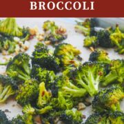 A pin image of a cookie sheet with roasted broccoli and garlic on it.