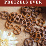 A pin image of seasoned pretzels spread out on a wooden board.
