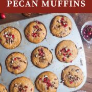A pin image of freshly baked cranberry orange muffins sprinkled with pecans still in the muffin tin.