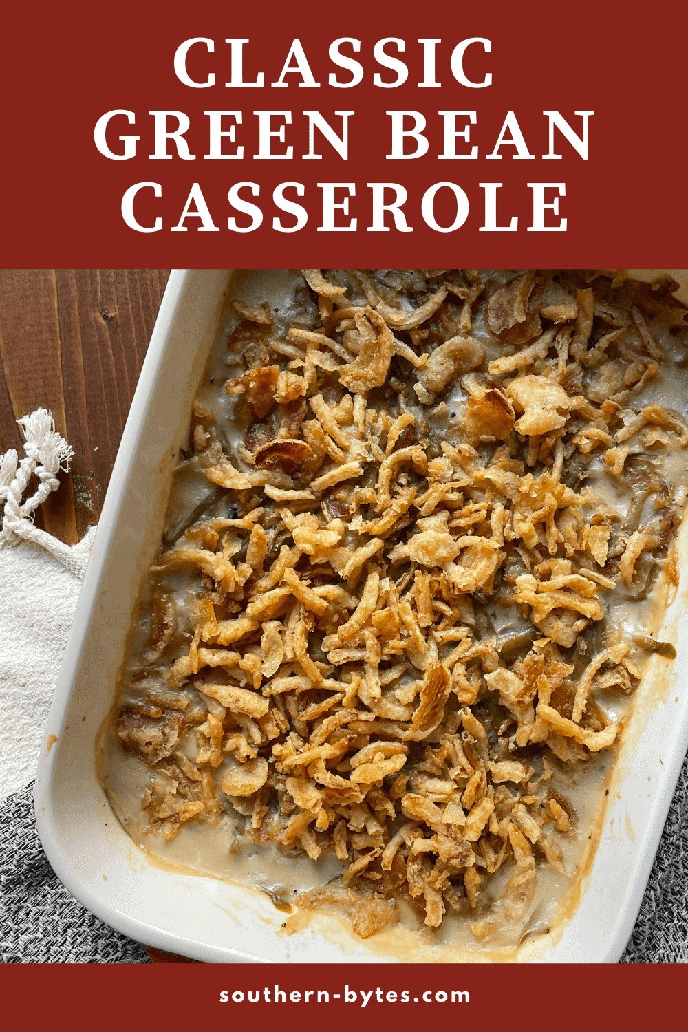 A pin image of green bean casserole covered in crispy onions in a baking dish.