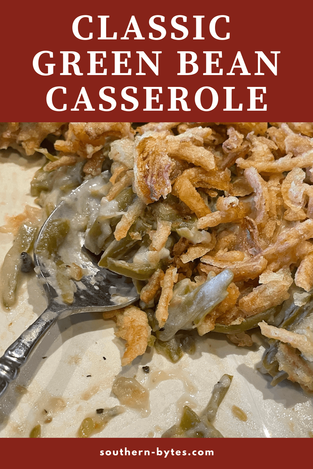 A pin image of green bean casserole covered in crispy onions in a baking dish with a spoon scooping it.