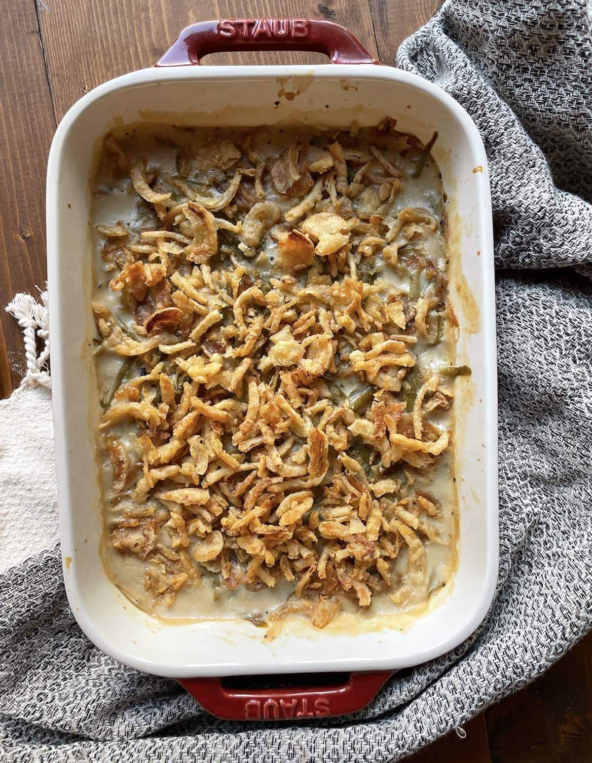 Green bean casserole covered in crispy onions in a baking dish.