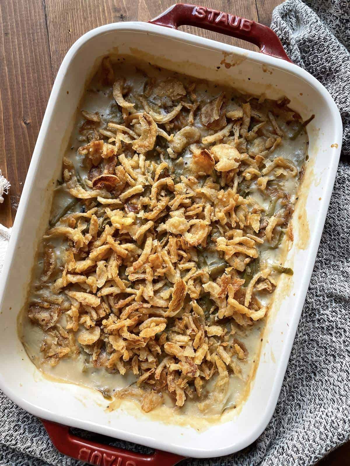 Green bean casserole covered in crispy onions in a baking dish.