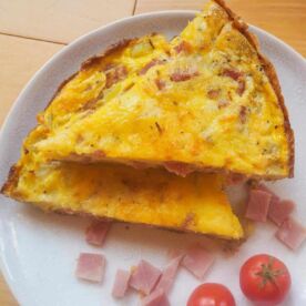 Two slices of ham and cheese frittata stacked on a white plate.