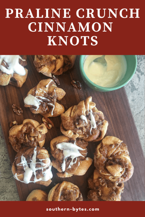 A pin image of a pile of praline crunch cinnamon knots on a brown cutting board and a bowl of icing.