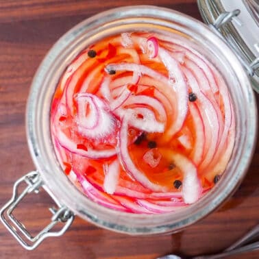 A closeup of a jar of pickled red onions.