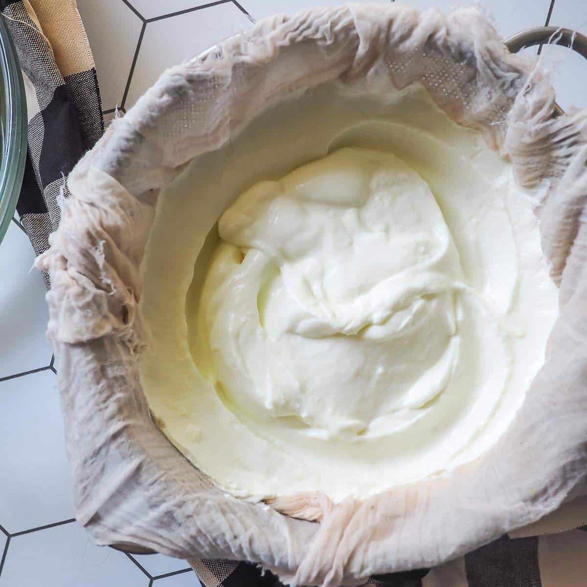 A bowl of yogurt straining in cheesecloth.