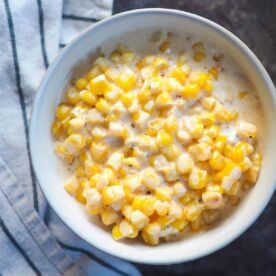 A white bowl of creamed corn.