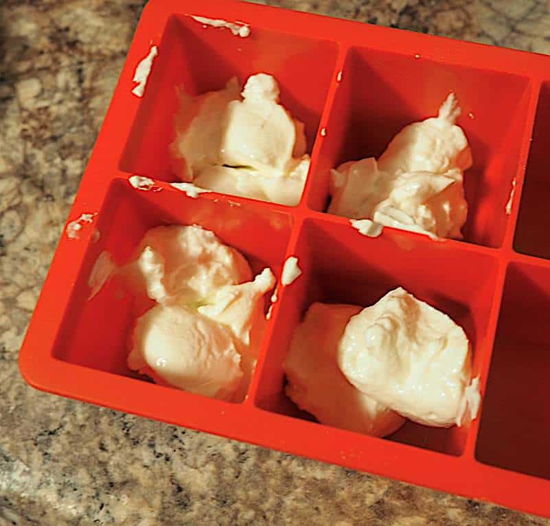 A red silicone tray with scoops of greek yogurt in it.