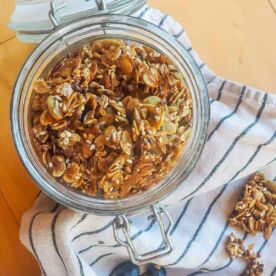 A jar of homemade granola with a striped dish towel.