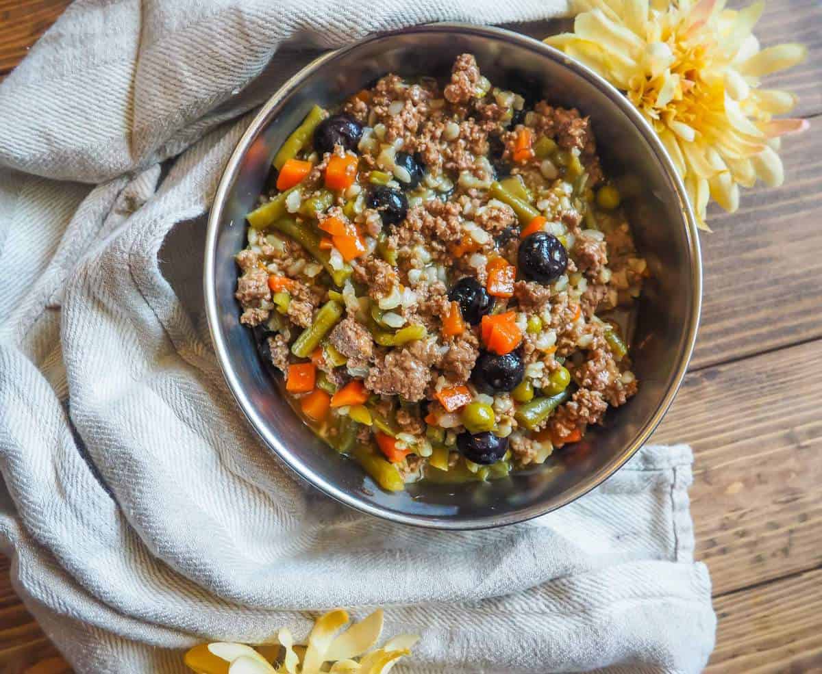 A small bowl of instant pot homemade ground beef dog food with rice, carrots, and green beans.