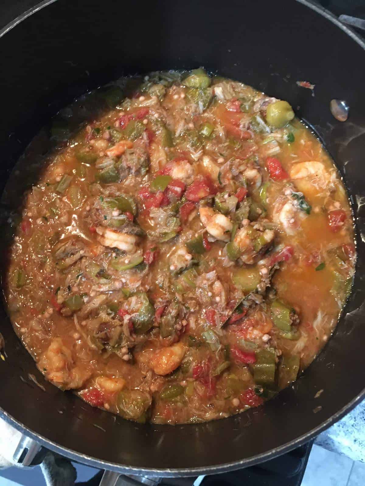 Seafood gumbo simmering in a black pot.