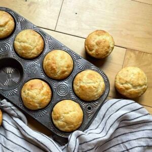 A pan of baked buttermilk muffins with a striped dish towel.