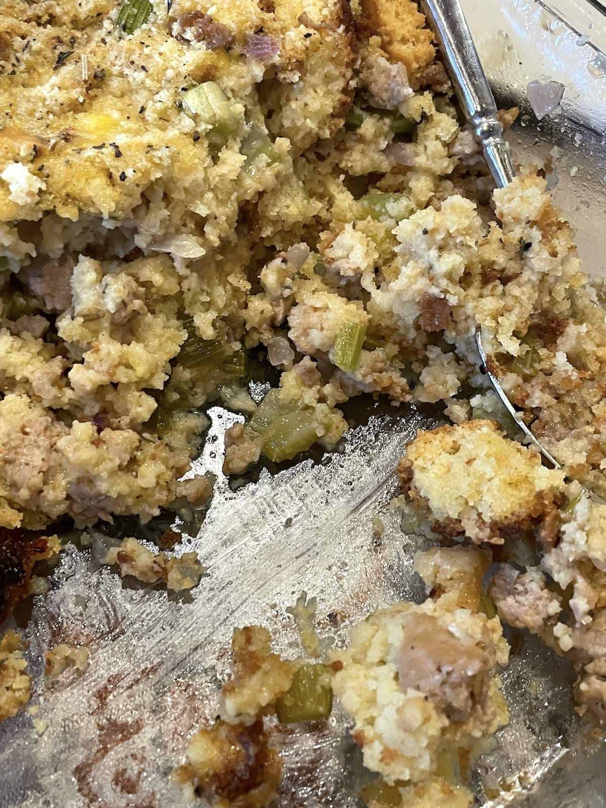 Southern cornbread dressing in a pan, partially scooped out.
