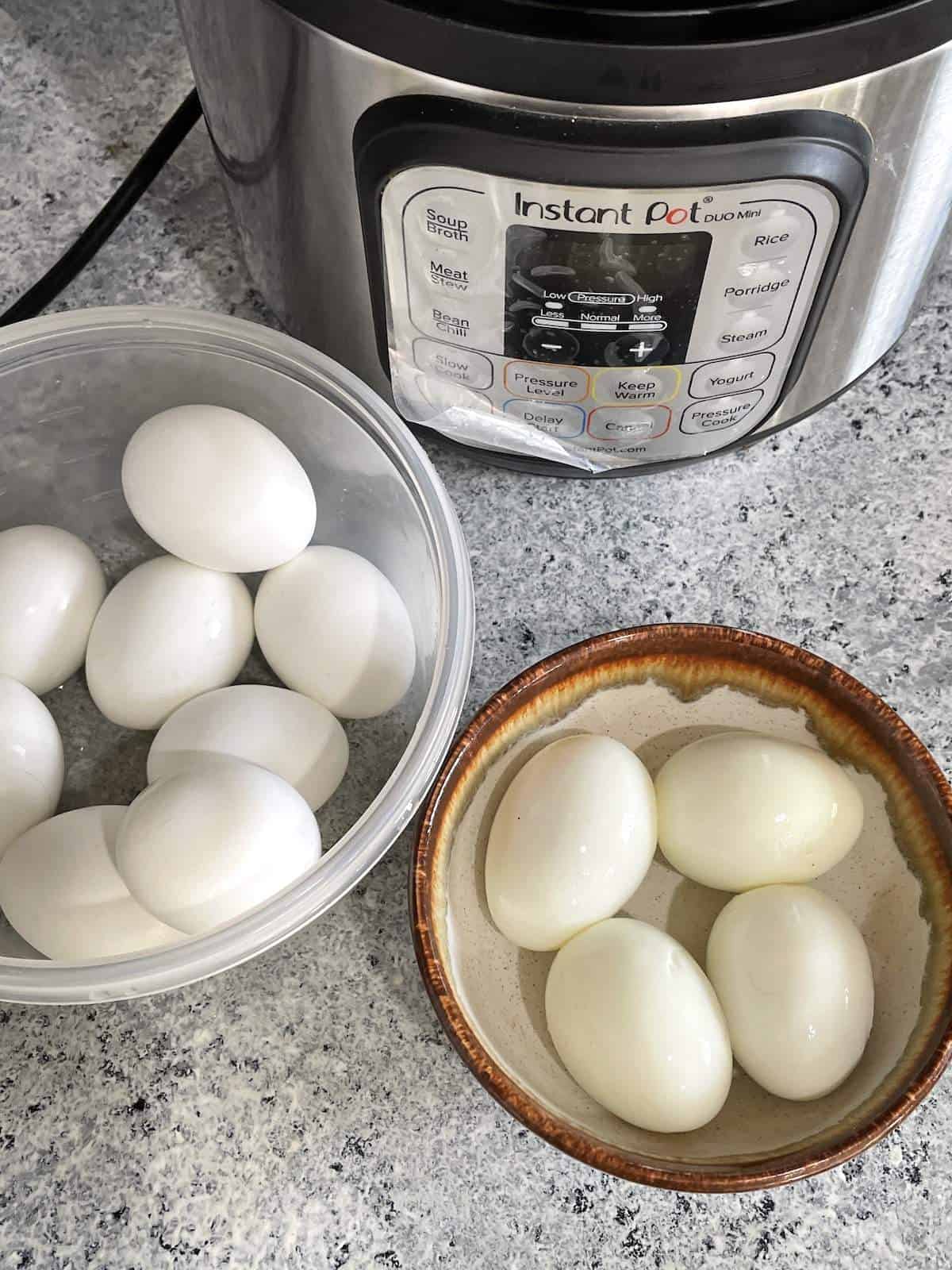An instant pot next to a bowl of hard boiled eggs, some peeled and some in their shell.