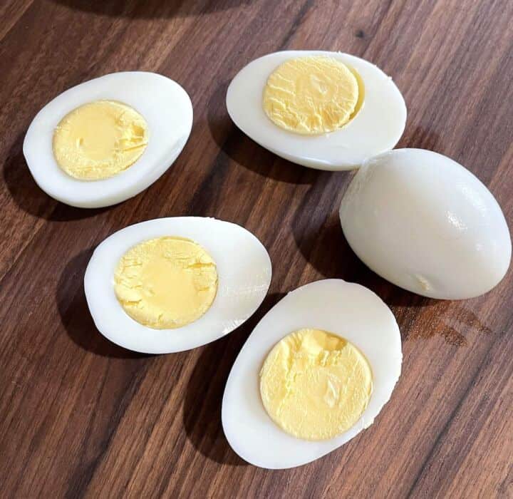 Sliced open hard boiled eggs on a wooden cutting board.
