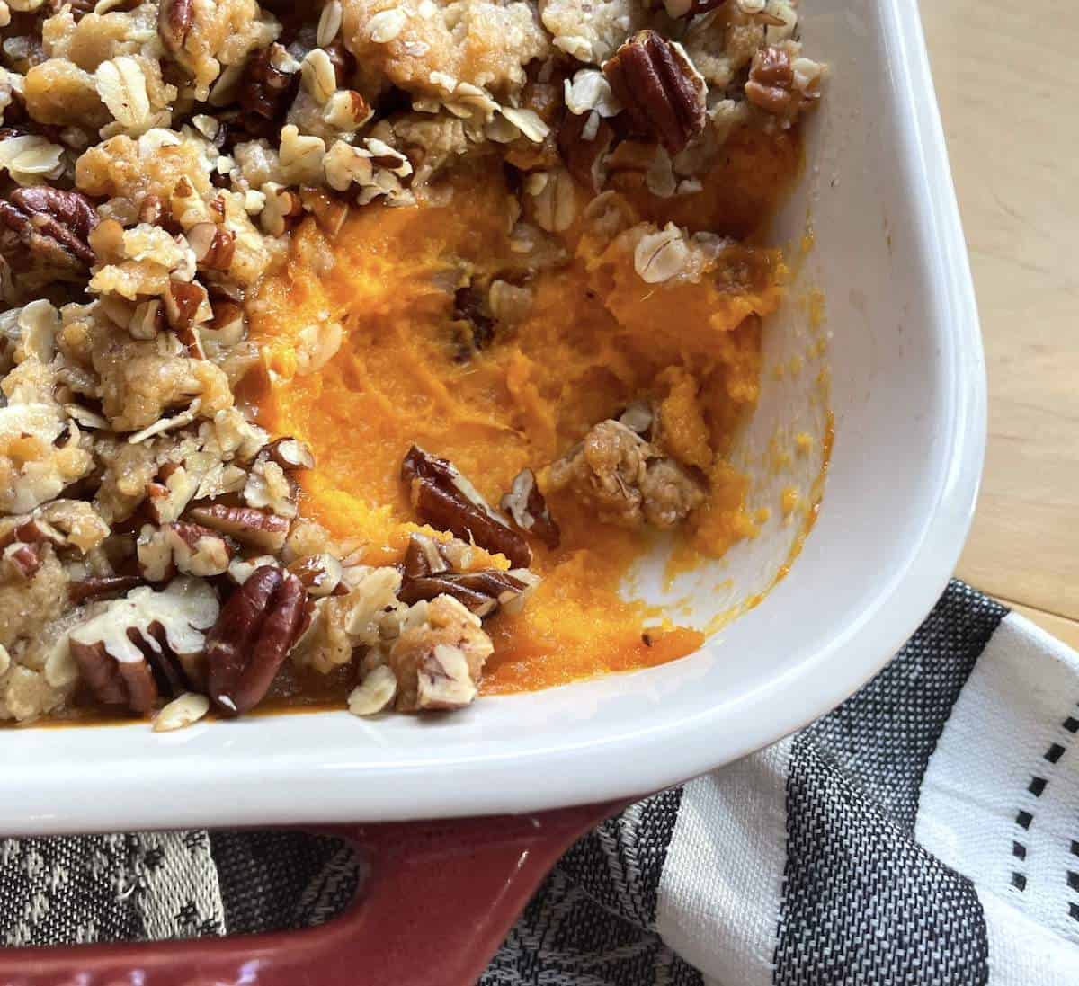 A pan of sweet potato casserole with a scoop missing.