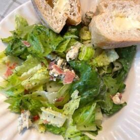 A bowl of royal street salad and two slices of buttered french bread.