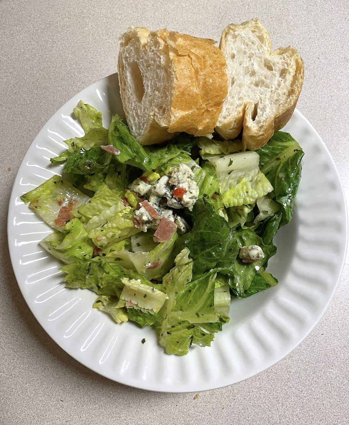 A bowl of royal street salad and two slices of french bread.