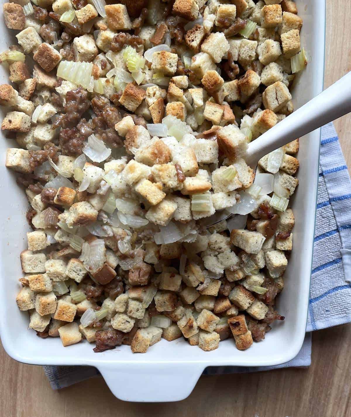 A pan of homemade stuffing with a white spoon.
