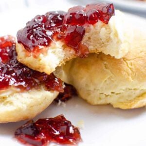 A pile of sour cream biscuits with jelly on them.