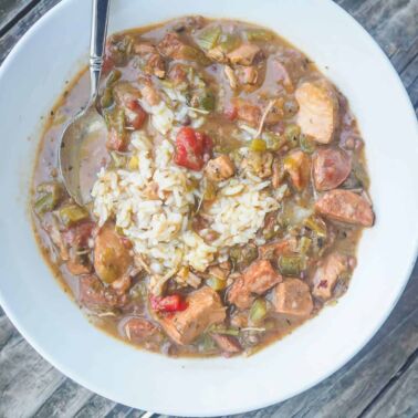 A white bowl of chicken and sausage gumbo.