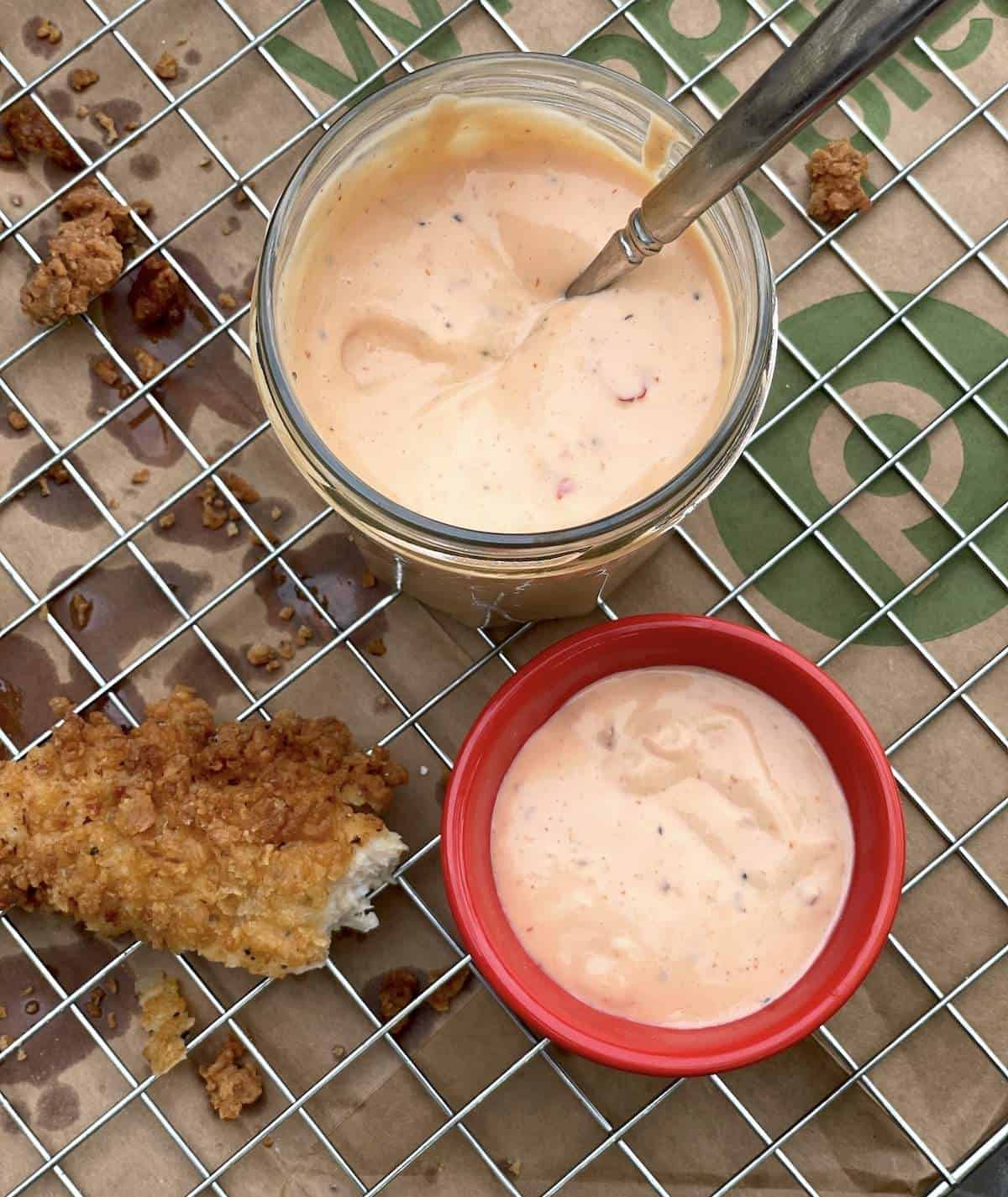 A jar of boom boom sauce, a bowl of boom boom sauce, and a chicken tender.