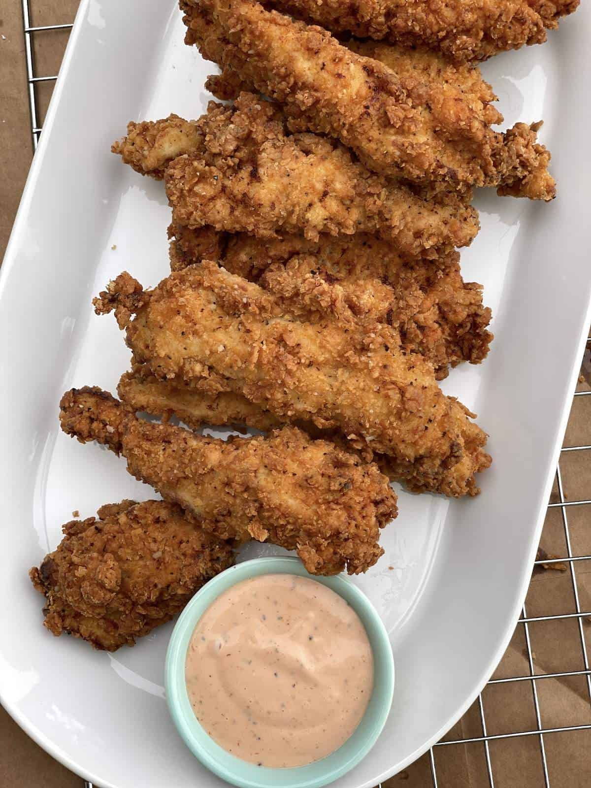 Golden fried chicken on a plate with Cane's dipping sauce.