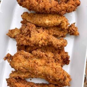 A white dish with crispy fried chicken tenders on it.