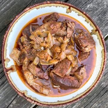 A bowl of crock pot boneless country style ribs with onions.