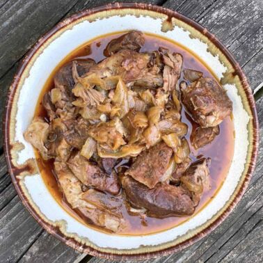 A bowl of crock pot boneless country style ribs with onions.