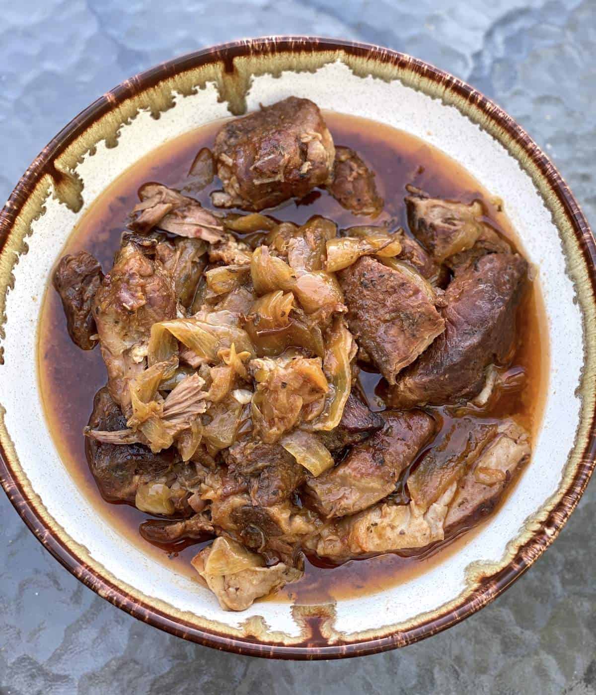 A bowl of slow cooker boneless country style ribs with onions.