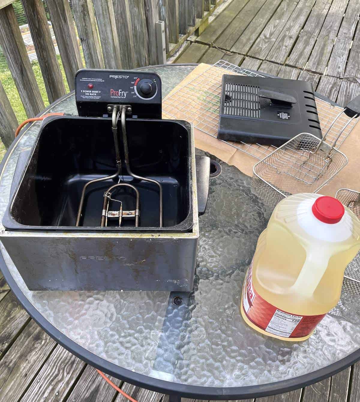 A deep fryer, peanut oil, and fryer baskets warming up to make fried chicken tenders.