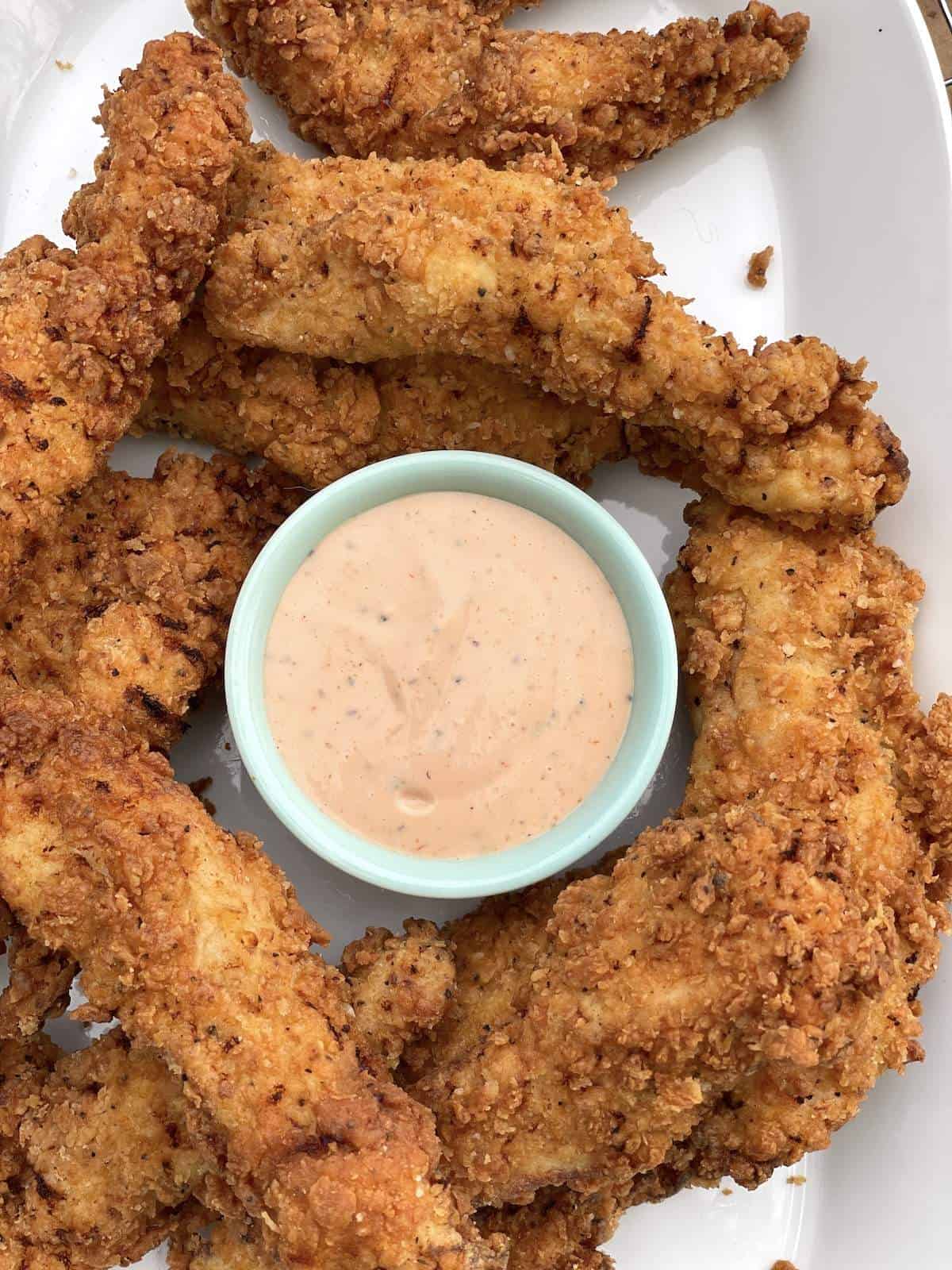 Fried Chicken Tenders with Cane's Sauce on a white platter.
