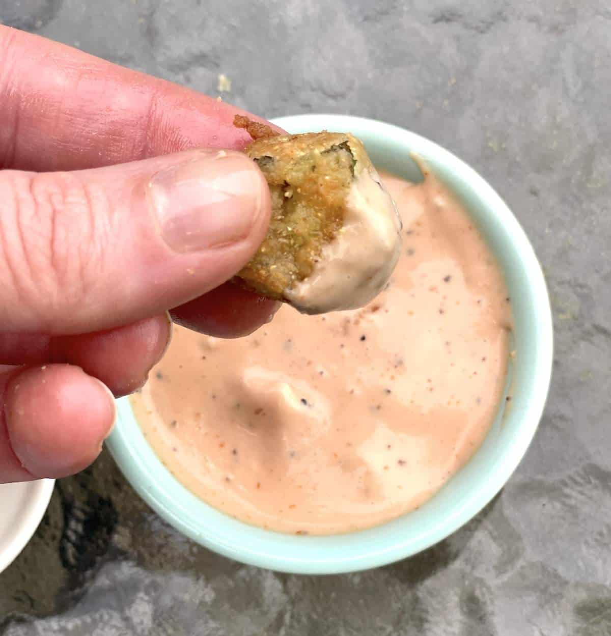 A fried okra pod dipped in Raising Cane's Sauce.