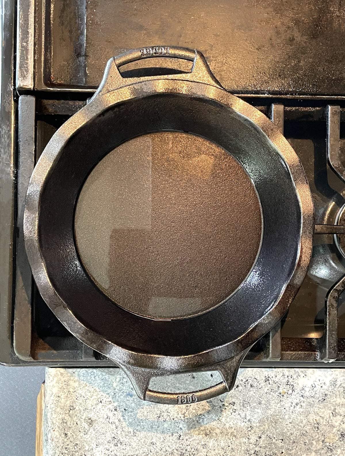 A cast iron pie pan on a stove with melted bacon grease in it.