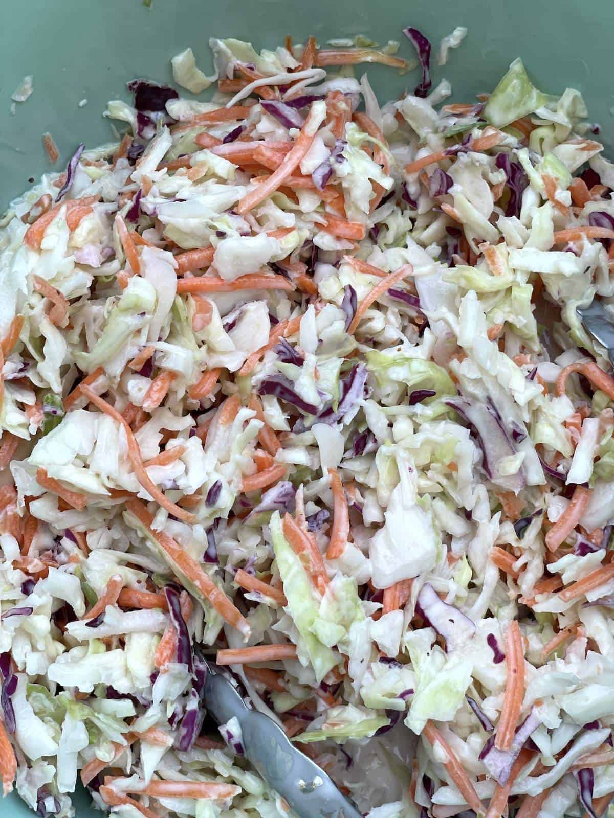 A big blue bowl of tangy southern coleslaw with shredded carrots up close.