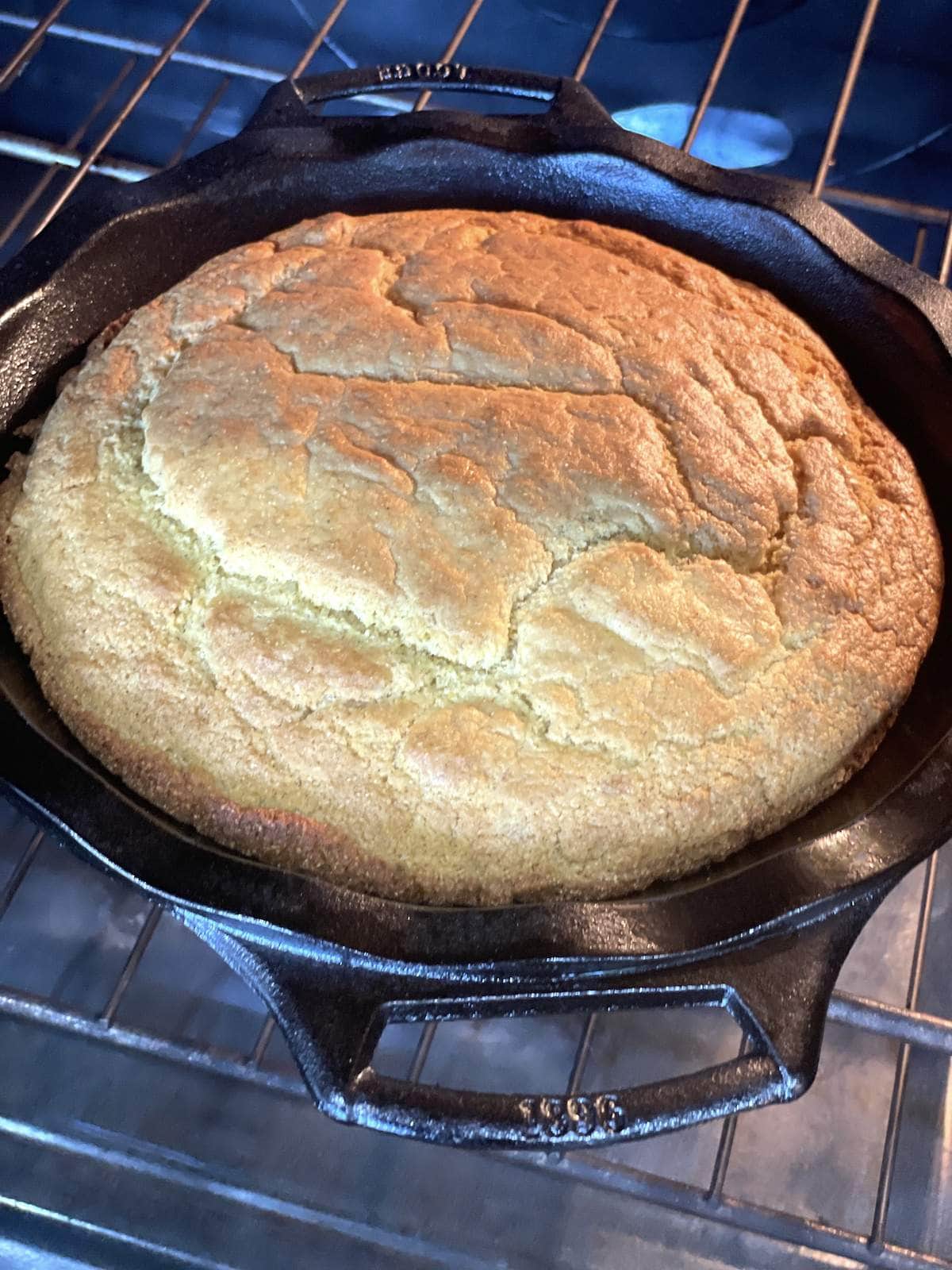 Southern cornbread in a cast iron pan, freshly baked, being removed from the oven.