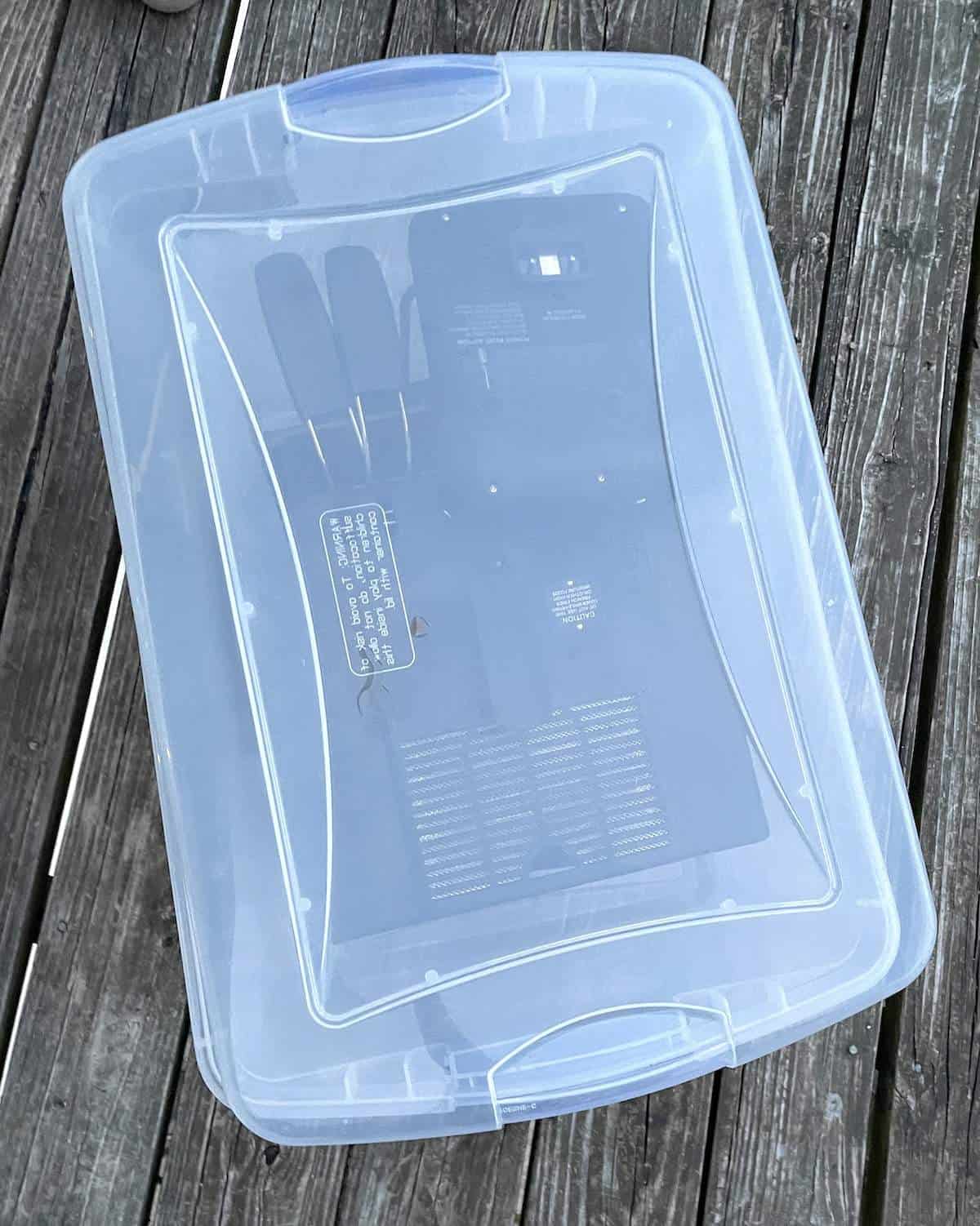 A clear plastic tote with a deep fryer stored inside of it.