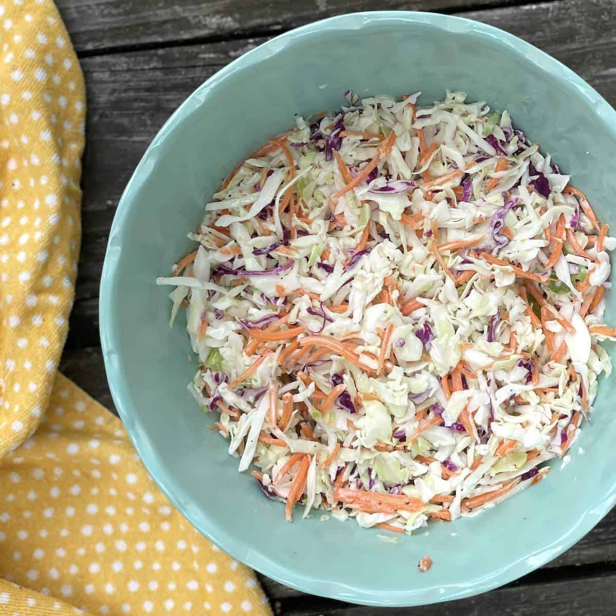 A big blue bowl of the best creamy southern coleslaw with shredded carrots.
