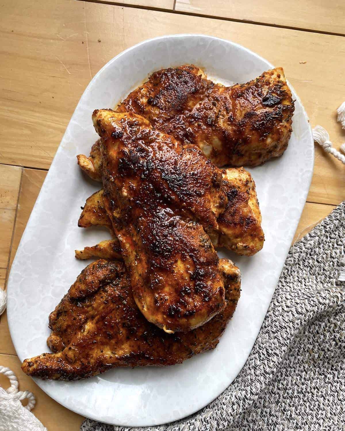 Juicy blackened chicken breasts on a white serving dish.