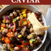 A pin image of a small bowl of cowboy caviar with black-eyed peas, black beans, corn, tomatoes, red onions, and cilantro with a vinegar based dressing and a side of tortilla chips.